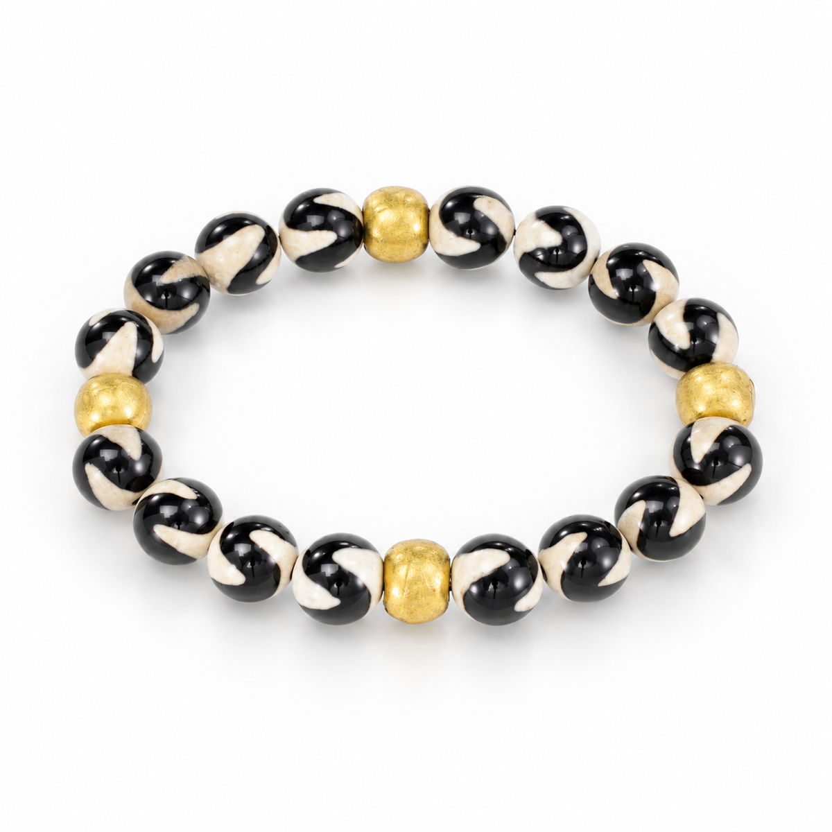 Angled view of glossy black-and-cream swirl agate beads and textured brass accents on a white background.