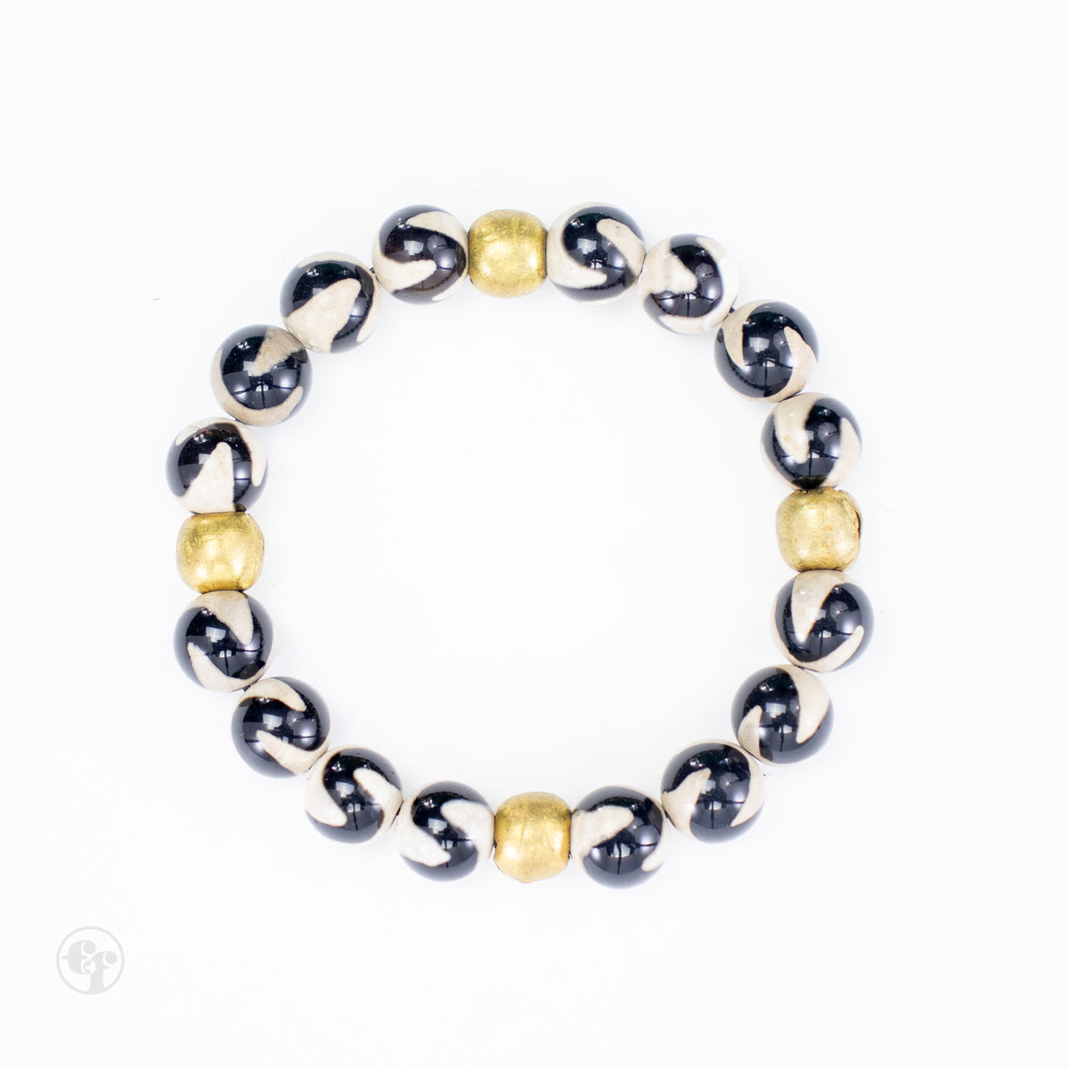 Top-down view of black-and-cream swirl agate beads with four rounded brass accent beads.