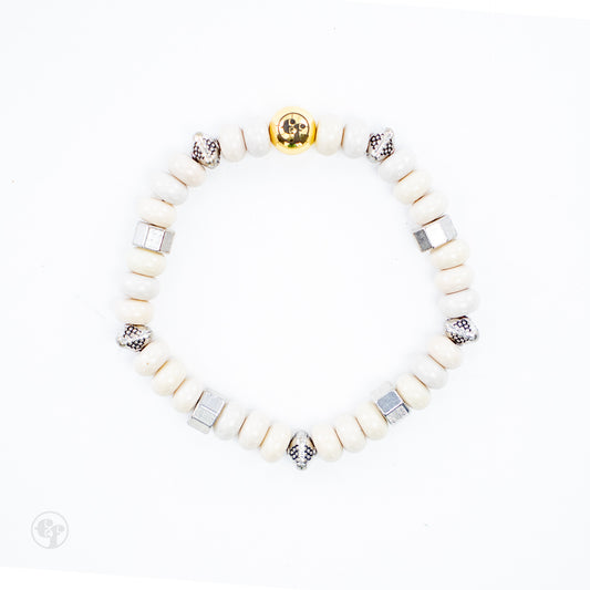 Top-down view of cream rondelle beads with silver-tone hexagonal and dotted accents and a polished gold-tone emblem bead.