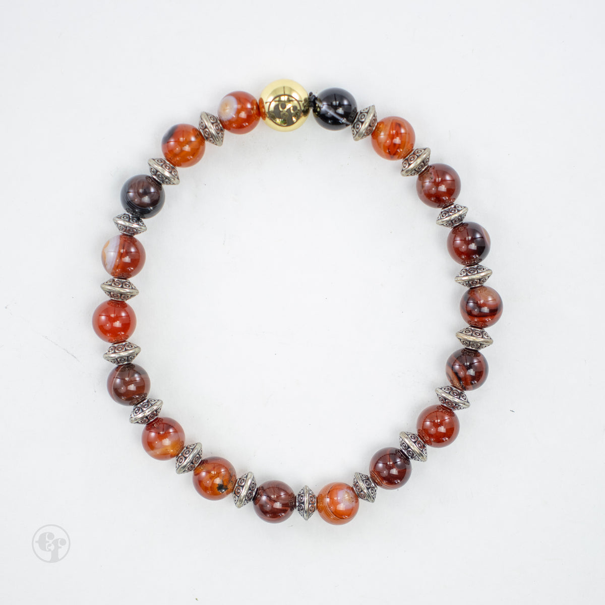 Top view of a bracelet with glossy red-orange, brown and dark round beads, ornate silver-tone spacers, and a polished gold-tone emblem bead.