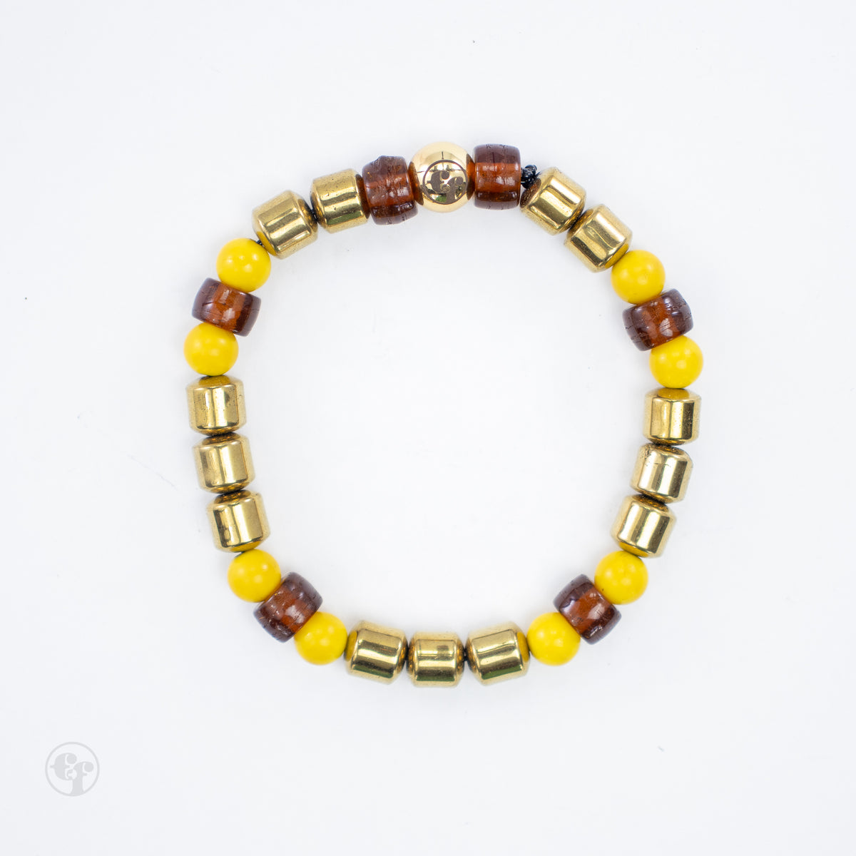 Top view of a yellow and amber-brown bead bracelet with grouped gold-tone barrel accents and a polished gold-tone emblem bead.